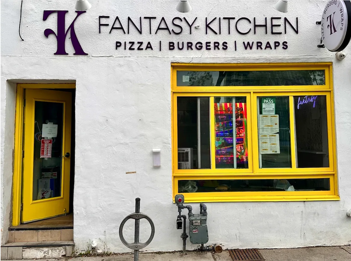The Fantasy Kitchen storefront at 195 Harbord Street: white wall, purple FK sign reading Pizza, Burgers, Wraps, and a yellow window frame